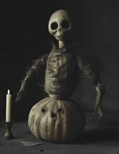 A creepy skeleton doll is sitting on a pumpkin with two holes and a candle next to it.