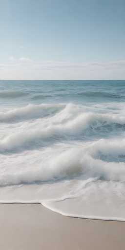 A stunning photograph captures the serene beauty of a beach at low tide. The foreground showcases wet, tan sand that glistens under the sunlight. Gentle waves, adorned with white foam, lap at the shore, creating a mesmerizing pattern as they recede. The ocean stretches out into the distance, its surface a deep, tranquil blue. Above, the sky is a brilliant azure, dotted with wispy clouds that add texture to the scene. The overall composition exudes a sense of calm and natural beauty, inviting viewers to immerse themselves in the peaceful coastal landscape.